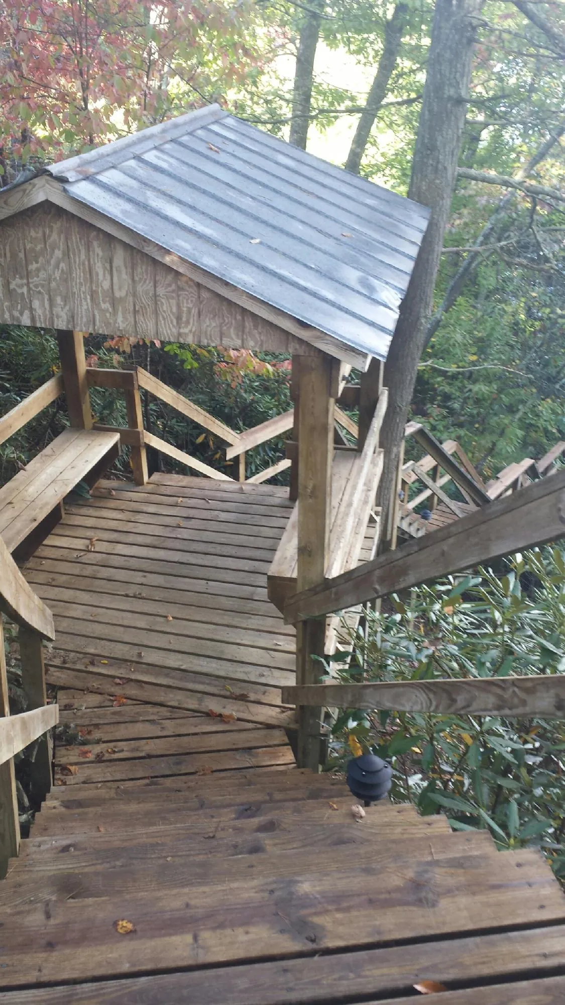 Metal roofed shelter over wooden steps on a wooded walkway — Skylight Repair & Installation work by our crew in Cabot